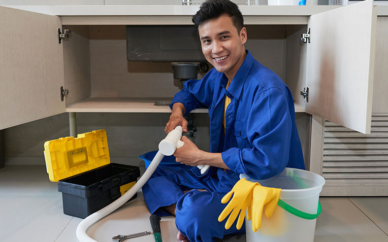 Plumber working on a home's plumbing system, Global Home Improvements services.
