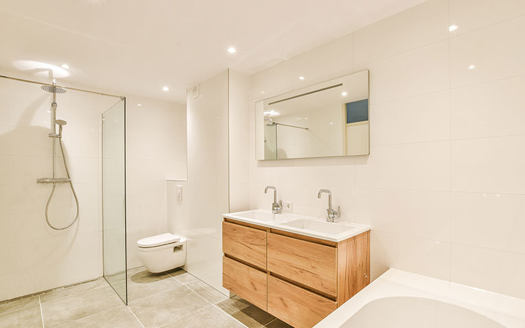 Newly renovated modern bathroom with sleek white tiles, floating vanity, and large mirror - bathroom remodeling services.