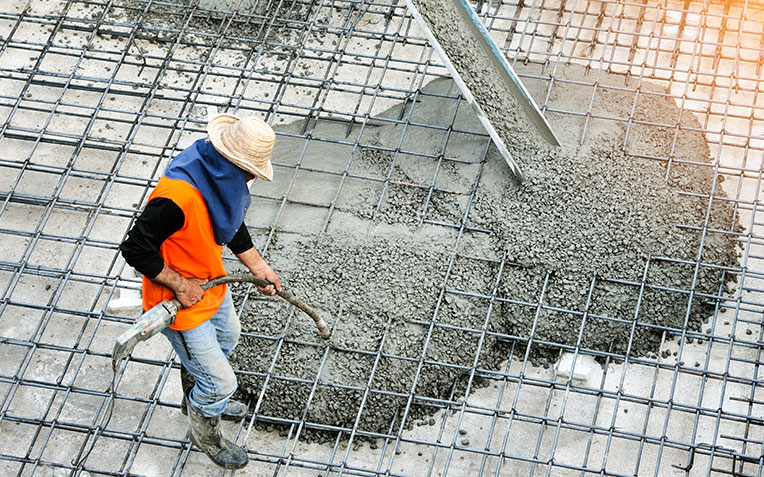 Concrete construction worker operating heavy machinery on a job site for Global Home Improvements.