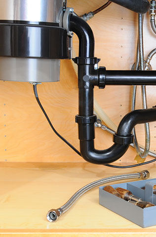 Plumbing pipes, fittings, and tools on a work surface in a home improvement setting.