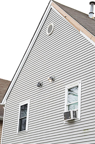 Closeup view of grey vinyl siding panels on a home exterior, highlighting home improvement services.